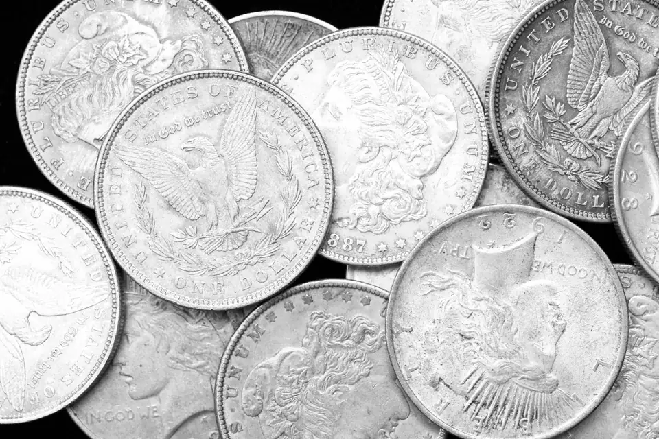 A pile of Morgan and Peace silver dollars, photographed in black and white